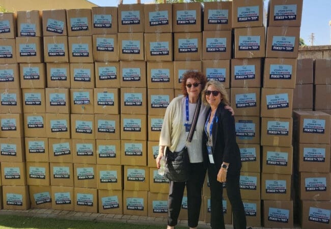 Two women standing in front of a stack of boxes.